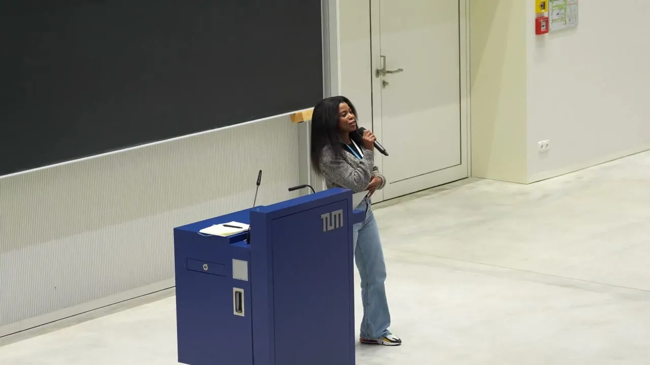 A speaker at a TUM lectern presenting in a lecture hall